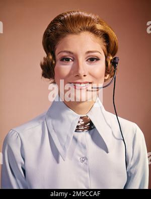 1960s 1970s SMILING WOMAN WEARING TELEPHONE HEADSET OFFICE RECEPTIONIST CALL CENTER SALESPERSON LOOKING AT CAMERA - kg3449 HAR001 HARS STYLE COMMUNICATION CENTER INFORMATION PLEASED JOY LIFESTYLE SALESPERSON CALL FEMALES JOBS STUDIO SHOT COMMUNICATING COPY SPACE LADIES PERSONS CONFIDENCE HEADSET EYE CONTACT SKILL OCCUPATION SELLING SKILLS OPERATOR HEAD AND SHOULDERS CHEERFUL LEADERSHIP REDHEAD PRIDE SUPERVISOR OCCUPATIONS PHONES SMILES RED HAIR TELEPHONES JOYFUL SALESWOMAN SALESWOMEN STYLISH CALM COOPERATION MID-ADULT MID-ADULT WOMAN CAUCASIAN ETHNICITY HAR001 OLD FASHIONED Stock Photo