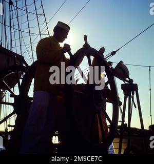 1960s ANONYMOUS SILHOUETTED US COAST GUARD ACADEMY CADET MANNING THE HELM OF THE TRAINING BARQUE EAGLE OFF NEW LONDON CT USA - ks7812 URW001 HARS COPY SPACE HALF-LENGTH PERSONS INSPIRATION UNITED STATES OF AMERICA MALES SAIL SYMBOLS SILHOUETTES CONFIDENCE TRANSPORTATION OUTLINE NORTH AMERICA NORTH AMERICAN COURSE DREAMS ADVENTURE HELM ACADEMY UNIVERSITIES SILHOUETTED DRAMATIC EXCITEMENT LOW ANGLE PRIDE OCCUPATIONS UNIFORMS HIGHER EDUCATION CADETS CONCEPT CONCEPTUAL COLLEGES STEER ANONYMOUS CADET MANNING SYMBOLIC CONCEPTS COOPERATION YOUNG ADULT MAN CT OLD FASHIONED REPRESENTATION Stock Photo