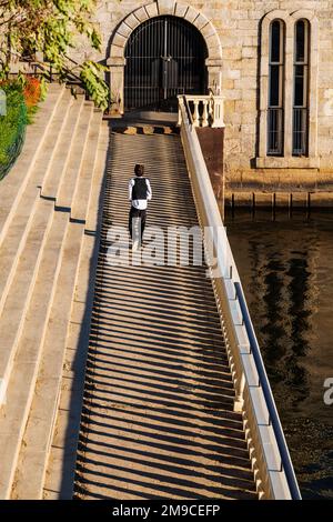 Young boy skipping happily along sunlit stone path; Fairmount Water Works; Philadelphia; Pennsylvania; USA Stock Photo