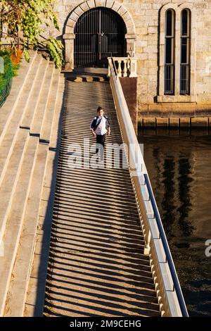 Young boy skipping happily along sunlit stone path; Fairmount Water Works; Philadelphia; Pennsylvania; USA Stock Photo