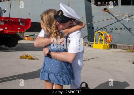 APRA HARBOR, Guam (May 16, 2022) – Senior Chief Master-at-Arms Shawn Stewart, assigned to the Emory S. Land-class submarine tender USS Frank Cable (AS 40), hugs his daughter after returning from patrol, May 16, 2022. Frank Cable has returned from conducting expeditionary maintenance and logistics in support of national security in the U.S. 7th Fleet area of operations. Stock Photo
