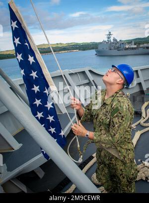 APRA HARBOR, Guam (May 16, 2022) - Machinery Repairman 3rd Class Sampson Patty, assigned to the Emory S. Land-class submarine tender USS Frank Cable (AS 40), raises the Union Jack as the ship moors pierside at Naval Base Guam, May 16, 2022. Frank Cable has returned from conducting expeditionary maintenance and logistics in support of national security in the U.S. 7th Fleet area of operations. Stock Photo