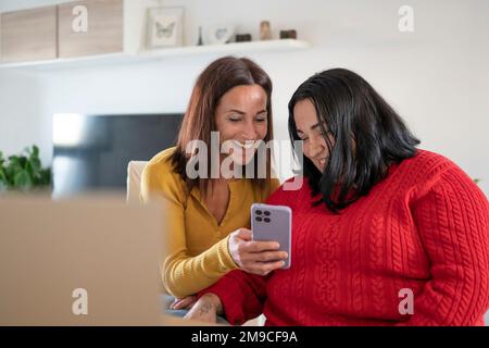 Two different friends looking at something funny on the phone. Stock Photo
