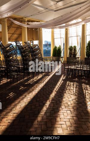 Sunlight streams through stacked event chairs; Fairmount Water Works; Philadelphia; Pennsylvania; USA Stock Photo