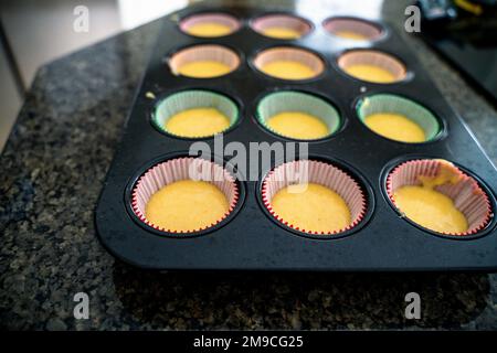 Cupcake Batter in Colored Liners on Countertop Stock Photo