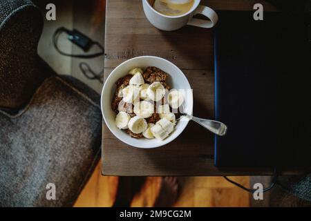 Chocolate Oatmeal with Bananas on Table with Laptop and Coffee Stock Photo