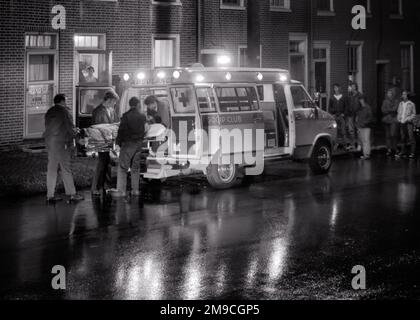 1970s EMERGENCY PERSONNEL LOADING A STRETCHER WITH PATIENT INTO AN AMBULANCE AT NIGHT AS WORRIED FAMILY AND NEIGHBORS STAND BY - m9604 HAR001 HARS LADIES PERSONS MALES RISK STRETCHER AILMENT TRANSPORTATION B&W SADNESS EMT NEIGHBORS HEALTHCARE LOADING DISASTER SUFFERING PREVENTION HEALING AND DIAGNOSIS EXCITEMENT EXTERIOR GURNEY HEALTH CARE BY IMPAIRMENT OCCUPATIONS TREATMENT HOSPITALS URGENT FACILITY AMBULANCES EMERGENCY MEDICAL TECHNICIAN EMTS FACILITIES POOR HEALTH AILING COOPERATION PERSONNEL TRANSIT BLACK AND WHITE DISEASE HAR001 OLD FASHIONED Stock Photo