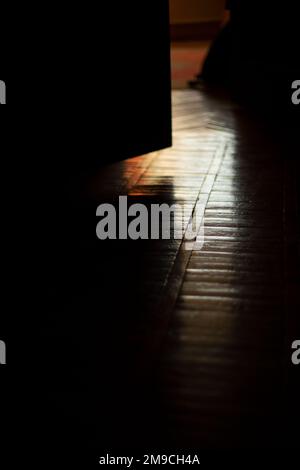 Light on parquet in room. Light from window in dark apartment. Stock Photo