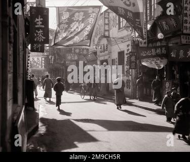 1920s 1930s CITY OF FORTUNE LATE AFTERNOON SUN SILHOUETTED PEDESTRIANS BANNERS SIGNS FUZHOU ROAD SHANGHAI CHINA - q335 HAR001 HARS SILHOUETTED CHARACTERS OCCUPATIONS CONCEPTUAL STYLISH AFTERNOON BANNERS BLACK AND WHITE HAR001 OLD FASHIONED Stock Photo