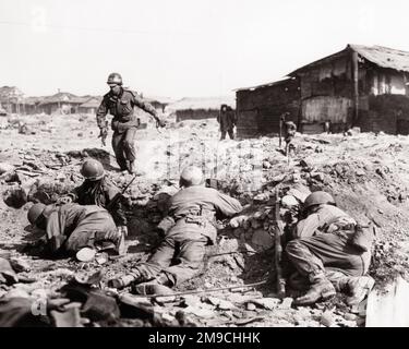 1950s 1951 US ARMY INFANTRY UNIT TAKES COVER FROM CHINESE COMMUNIST SMALL ARMS FIRE AT EDGE OF KOREAN VILLAGE SOUTH KOREA  - q987 CPC001 HARS EXCITEMENT UNIT OCCUPATIONS POLITICS UNIFORMS 1951 KOREAN CONCEPTUAL SQUAD KOREAN WAR KOREA POLICE ACTION TAKES ARMISTICE COMMUNIST INFANTRY BLACK AND WHITE OLD FASHIONED Stock Photo