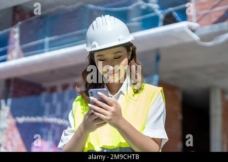 female architect looking at blueprints on her smartphone Stock Photo