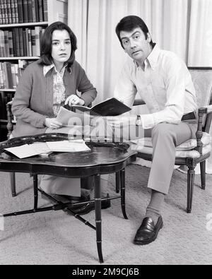 1970s COUPLE REVIEWING DOCUMENTS PAPERS BILLS SCHEDULES SITTING BY COFFEE TABLE LOOKING AT CAMERA UNSMILING SERIOUS EXPRESSIONS - s20806 HAR001 HARS COMMUNICATION BILL TEAMWORK INFORMATION WORRY LIFESTYLE FEMALES MARRIED SPOUSE HUSBANDS HOME LIFE COPY SPACE FRIENDSHIP HALF-LENGTH LADIES PERSONS THOUGHTFUL MALES EXPRESSIONS B&W PARTNER EYE CONTACT GOALS DOCUMENTS OPPORTUNITY CANDID CONCERN CONNECTION REVIEWING SUPPORT SINCERE SOLEMN COOPERATION FOCUSED INTENSE MID-ADULT MID-ADULT MAN MID-ADULT WOMAN TOGETHERNESS WIVES BLACK AND WHITE CAREFUL CAUCASIAN ETHNICITY EARNEST HAR001 INTENT Stock Photo