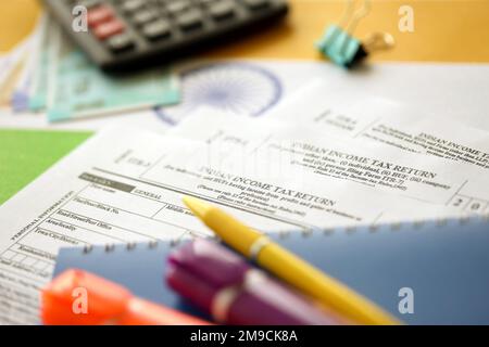 KYIV, UKRAINE - MAY 4, 2022 Indian income tax return blank form with pen and indian rupees bills on indian country flag close up. Annual tax report concept Stock Photo