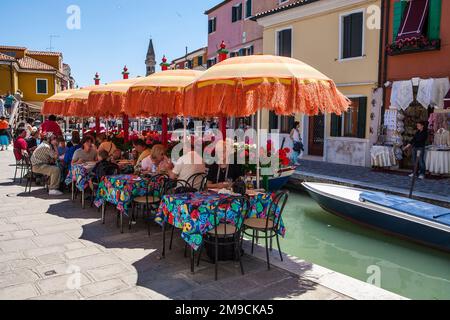People eating and relaxing at a local cafe next to a canal in Venice, Italy. Stock Photo