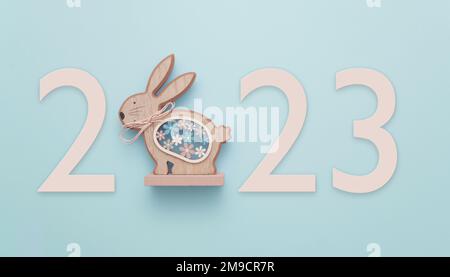 In celebration of Easter or the Chinese New Year 2023, the year of the Rabbit. A wooden rabbit on a blue background displaying the number 2023. Stock Photo