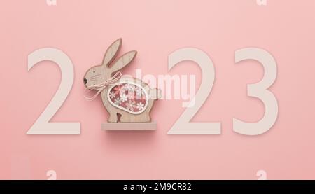 In celebration of Easter or the Chinese New Year 2023, the year of the Rabbit. A wooden rabbit on a red background displaying the number 2023. Stock Photo