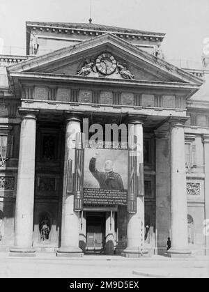 1936 , 27 may , TRIESTE , ITALY : Italian Fascist  PROPAGANDA , the BENITO MUSSOLINI gigantic painted portrait image enlargement in front of the BORSA MERCI ( Stock Exchange building ) entrance door . The image celebrated the Mussolini speech to the crowd claiming the Italian conquest of Ethiopia and the proclamation of the EMPIRE OF ITALY the day 9 may 1936 in Rome . Unknown photographer . - HISTORY- FOTO STORICHE - ROMA - FASCISMO - FASCISTA - FASCISM - ITALIA  - 30's - '30  - ANNI TRENTA -  XX CENTURY - NOVECENTO - PROPAGANDA  - CATTIVO GUSTO - KITSCH - FASCIO LITTORIO -  ARCHITETTURA - ARC Stock Photo