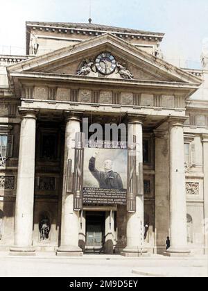 1936 , 27 may , TRIESTE , ITALY : Italian Fascist  PROPAGANDA , the BENITO MUSSOLINI gigantic painted portrait image enlargement in front of the BORSA MERCI ( Stock Exchange building ) entrance door . The image celebrated the Mussolini speech to the crowd claiming the Italian conquest of Ethiopia and the proclamation of the EMPIRE OF ITALY the day 9 may 1936 in Rome . Unknown photographer . DIGITALLY COLORIZED . - HISTORY- FOTO STORICHE - ROMA - FASCISMO - FASCISTA - FASCISM - ITALIA  - 30's - '30  - ANNI TRENTA -  XX CENTURY - NOVECENTO - PROPAGANDA  - CATTIVO GUSTO - KITSCH - FASCIO LITTORIO Stock Photo