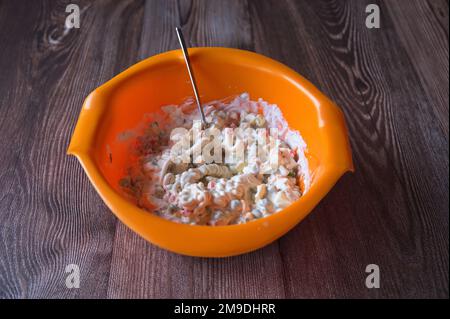 Preparing French salad in orange plastic bowl Stock Photo