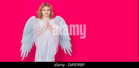 Angel prayer kids. Valentine's day. Blonde cute child with angel wings on a yellow studio background. Banner for website header design. Stock Photo