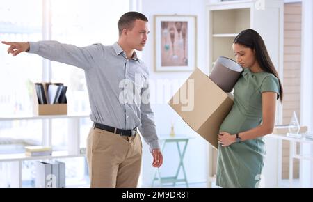 Get out. a handsome young businessman standing in the office and firing his pregnant employee. Stock Photo