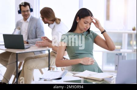 I think I should take a sick day. a young pregnant businesswoman sitting in the office and feeling stressed. Stock Photo