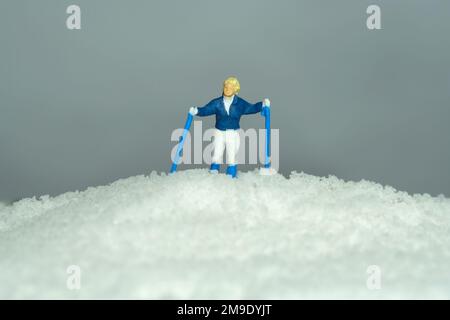 Miniature people toy figure photography. Winter sport. A women snow climber mountaineer standing on the top of mountain. Image photo Stock Photo