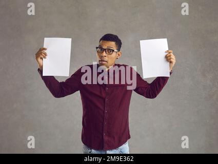 Confused black man holding two blank paper banners and trying to choose between them Stock Photo