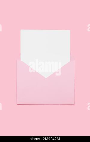 Closeup on blank empty white paper card in pink opened envelope isolated on pink pastel color background. Love letter minimal concept. Conceptual layout template with text place on postcard. Mock-up  Stock Photo