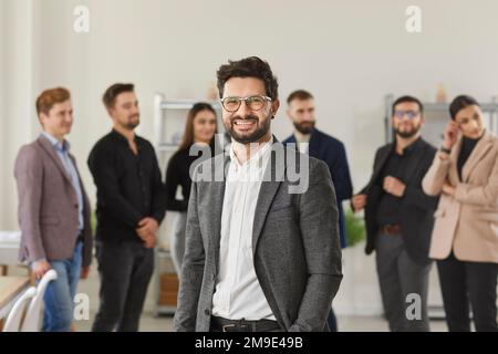 Portrait of successful, intelligent and cheerful leader against background of his business team. Stock Photo