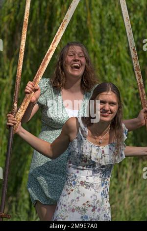 Two young girls swinging, Mecklenburg-Western Pomerania, Germany Stock Photo