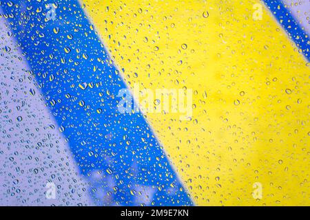Raindrops with ukraine flag background, raindrops on glass with colors of ukraine flag. Raindrops on window on glass background. Stock Photo