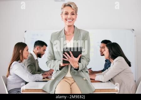 Feeding information into the system. a mature businesswoman using her digital tablet during a meeting. Stock Photo