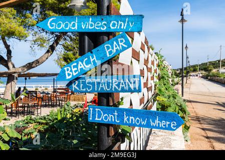 Ksamil, Albania - September 11, 2021: Wooden pointing arrows on the fence specify the direction to beach bar and restaurant in Ksamil, Albania. Stock Photo