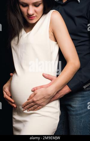 man hugs the belly of a pregnant girl. Couple is expecting a baby ...