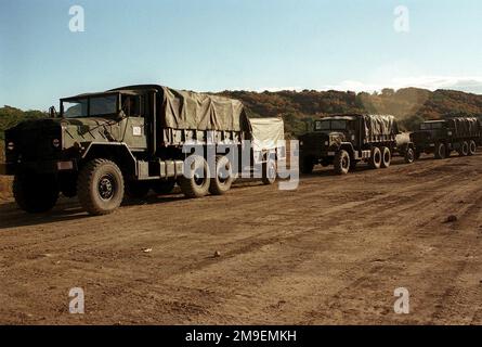 Left side front view of a US Marine convoy of M923A1 (6X6) 5-ton cargo trucks with two wheeled trailers in tow. The Marines, from Headquarters Battery, 3rd Battalion, 12th Marines from Marine Corps Base, Camp Hansen, Okinawa, Japan, arrive at Ojojihara Base Camp for an artillery relocation shoot. Subject Operation/Series: OJOJIHARA ARTILLERY RELOCATION SHOOT Base: Ojojihara Base Camp Country: Japan (JPN) Stock Photo
