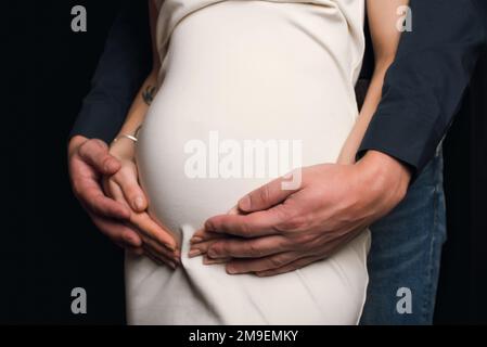 man hugs the belly of a pregnant girl. Couple is expecting a baby ...