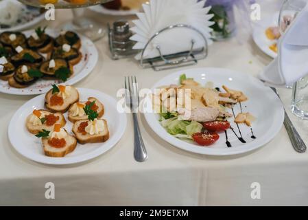 Caesar salad and other various snacks on the festive table in the restaurant Stock Photo