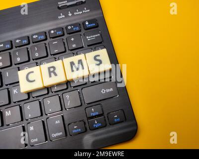 Black keyboard and toys word with the word CRMS on yellow background. Stock Photo