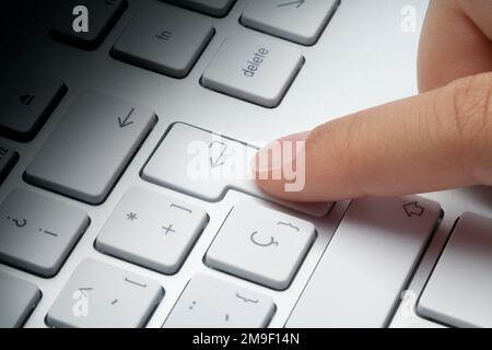 Index finger pressing enter key at keyboard. Fade light effect on keyboard. Stock Photo