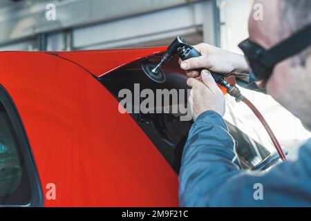 Mechanic with safety glasses prepares for spoiler replacement removing the old one. High-quality photo Stock Photo