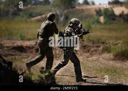 German soldiers assigned to the 212th Panzergrenadier Battalion, 21st Panzer Brigade, 1st Panzer Division, move to cover during a live-fire exercise as part of Defender Europe at Oberlausitz Training Area, Germany, May 19, 2022. Defender Europe 22 is a series of U.S. Army Europe and Africa multinational training exercises in Eastern Europe. The exercise demonstrates U.S. Army Europe and Africa’s ability to conduct large-scale ground combat operations across multiple theaters supporting NATO. Stock Photo