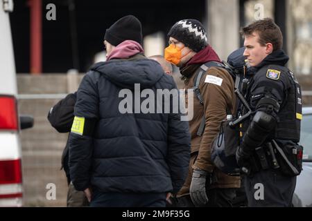 Hessen, Germany. 18 January 2023, Hessen, Frankfurt/Main: Police officers stand with an activist at the logistics center during the eviction of the occupation in Fechenheim Forest. The squatters are protesting against the planned expansion of the A66 with the Riederwald Tunnel, as around 1000 trees will have to be felled for this. Photo: Sebastian Gollnow/dpa Credit: dpa picture alliance/Alamy Live News Credit: dpa picture alliance/Alamy Live News Stock Photo