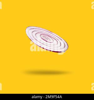 A slice of levitating red onion isolated on yellow background Stock Photo