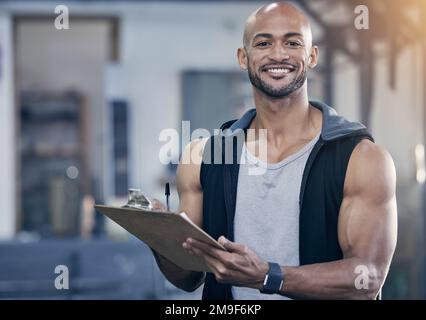 Young bodybuilder writing on a clipboard Stock Photo - Alamy
