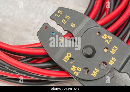 Close shot of Chinese made unbranded wire stripper & wire cutter for 26-10AWG wire (see Notes) with coiled connector cables. Stock Photo
