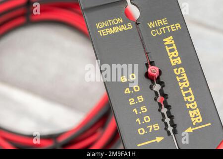 Close shot of Chinese made unbranded wire stripper & wire cutter for 26-10AWG wire (see Notes) with coiled connector cables. Stock Photo