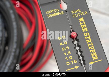 Close shot of Chinese made unbranded wire stripper & wire cutter for 26-10AWG wire (see Notes) with coiled connector cables. Stock Photo