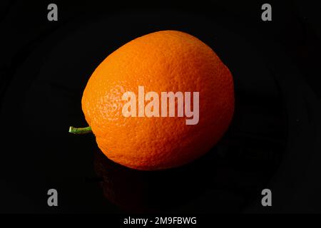 Isolated ripe orange fruit in close-up view. Black background. white and yellow orange peel. vitamin and healthy eating concept. vegetarian lifestyle. Stock Photo