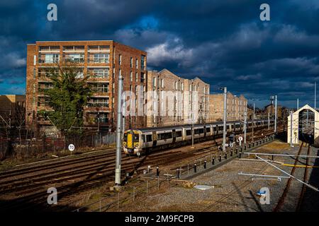Great Northern train arrives at Cambridge Railway Station passing new build housing in the brownfield Cambridge Ironworks developmen. Stock Photo